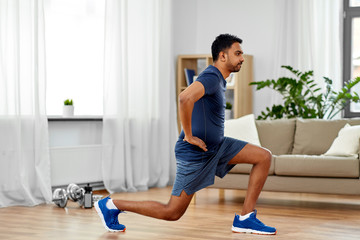 fitness, sport and healthy lifestyle concept - indian man exercising and doing lunge at home - obrazy, fototapety, plakaty