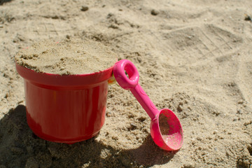 Baby red bucket and pink scoop in the sandbox