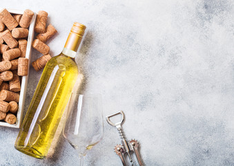 Bottle and glasses of white wine with box of corks and crkscrew opener on stone kitchen table...