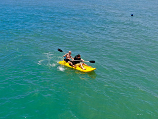 Aerial view of strong young active men kayaking on the clear blue  turquoise water of the ocean. Active vacation. Praia do Forte, Brazil