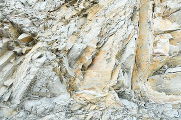 Fototapeta na wymiar Steep clay rock with sharp edges, covered with many cracks and chips