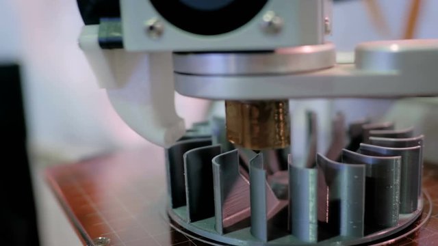 3D printing, additive technologies, industrial and manufacturing concept - 3D printer machine printing plastic workpiece look like metal at futuristic technology exhibition - close up shot