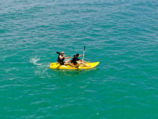 Aerial view of strong young active men kayaking on the clear blue  turquoise water of the ocean. Active vacation. Praia do Forte, Brazil