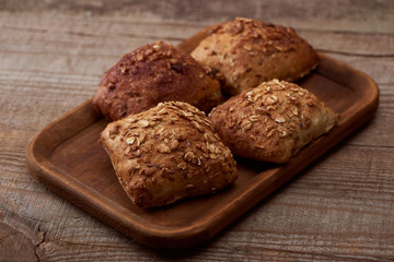 Obraz na płótnie Canvas fresh baked buns with grains on wooden board on rustic table