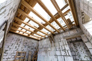 House room interior under construction and renovation. Energy saving walls of hollow foam insulation blocks, wooden ceiling beams and roof frame.