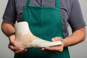 close up of orthopedic shoemaker hands presenting a wooden last