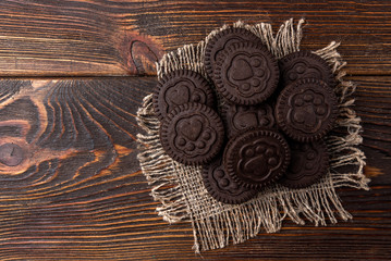 Chocolate cookies with milk filling on dark wooden background.