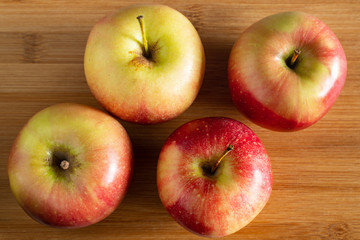 four beautiful red yellow apples lying on a wooden background