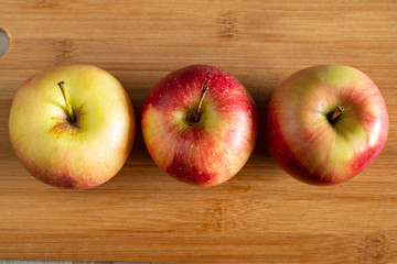 three beautiful red-yellow apples lying on a wooden background