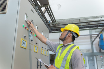 Asian electric engineer holding clipboard for checking and monitoring the electrical system in the control room,Technician thailand people working