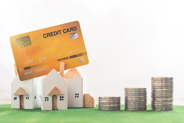 Property investment, Miniature house model with credit card and money coin stack on Simulation grass, white background, financial concept
