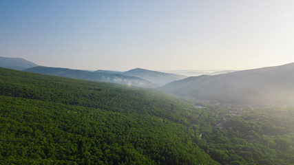 Aerial view of Caucasus mountain with haze and forest. Morning fog over the forest.