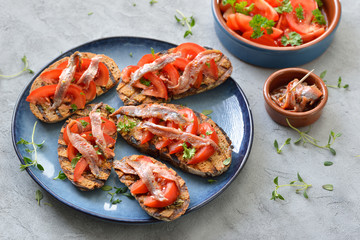 Gegrillte kleine Brotscheiben mit Olivenöl und Käutern, frischen Tomaten und...