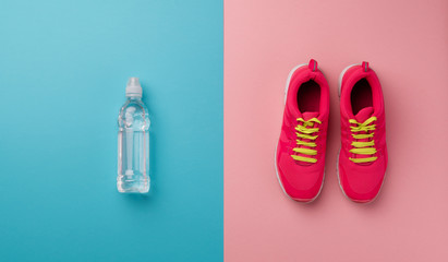Studio shot of running shoes and water bottle on color background. Flat lay.