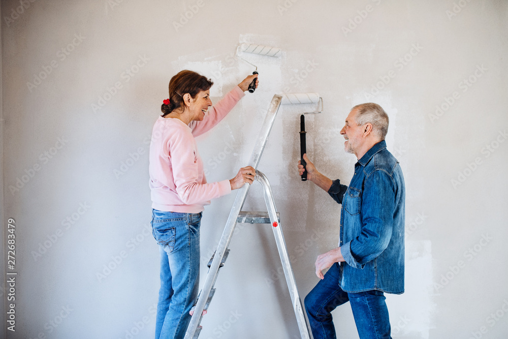 Wall mural senior couple painting walls in new home, relocation concept.