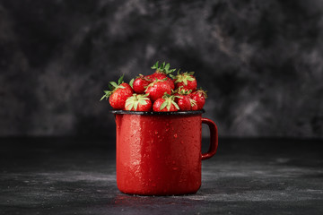Strawberries in a cup on the dark concrete background