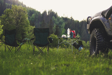 Picnic in the mountains with folding chairs and a table. The car and the rubber wheel. Carpathian mountains