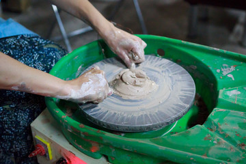 A novice student in the first lesson in pottery tries to make a product from clay on a potter's...