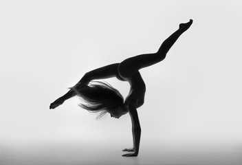 Gymnast with long hair and legs standing on hand in the string