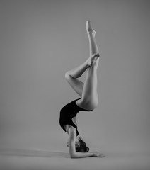 Flexible girl with long legs standing on hand