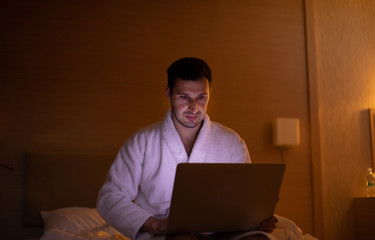 Man chatting on laptop in bed instead of sleeping, late night