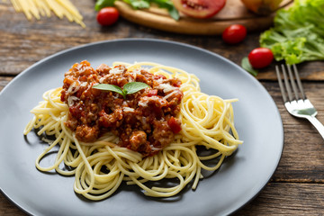 Spaghetti on black plate on wooden background. top view