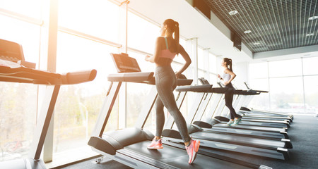 Fototapeta na wymiar Woman running on treadmill at panoramic window