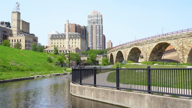 Cityscape scene of downtown Minneapolis, as seen from Mill Ruins Park. View of the Stone Arch bridge on sunny spring day