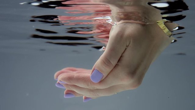 underwater view of woman hand immerse into the water and reflecting in water surface