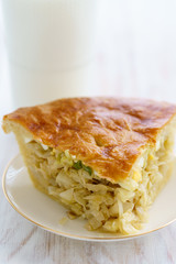 Cabbage pie on a porcelain plate. High resolution, white wooden background