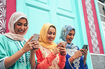 Young Muslim friend using mobile smartphones in the college - Happy Arabian girls addicted to new technology app cellphone for social media - Millennial, religion, generation z and technology concept - obrazy, fototapety, plakaty