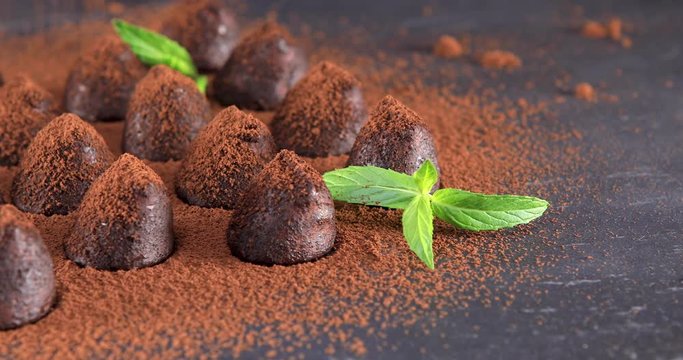 Powdering with cocoa delicious chocolate truffles on slate closeup. Dolly shot 4k