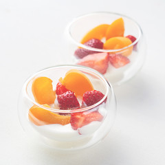Light vitamin healthy dessert of sliced strawberry, apricot and cornflakes with cream in glass creamers