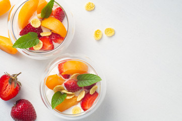 Vitamin dessert of fresh strawberries, apricots and cornflakes with cream on a white background