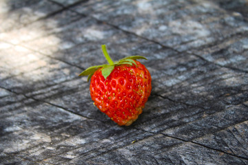 One little strawberry on the wooden old table, background