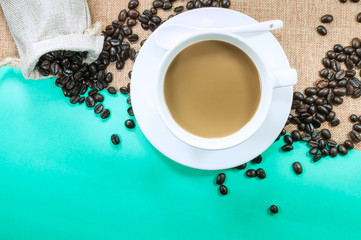 Cup of fresh coffee with coffee beans on burlap warm cup on brown background top view with free space for text