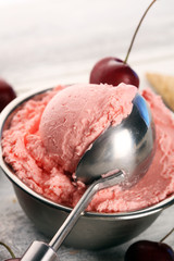 Cherry and vanilla ice cream scoop with fresh cherries and mint on a rustic background