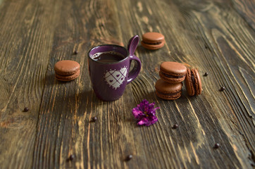 Macarons with chocolate filling and cup of coffee on dark wooden background