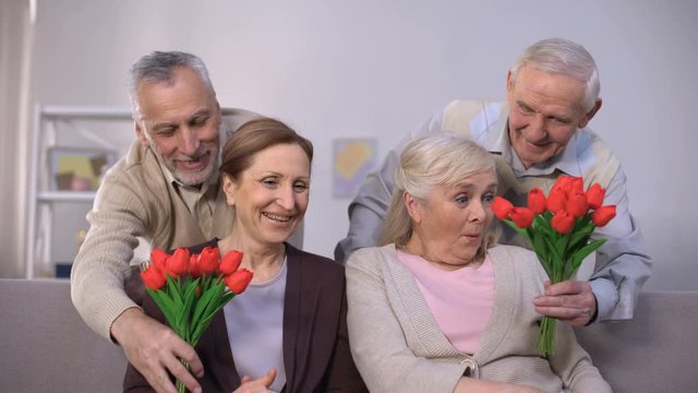 Old men presenting bunches of tulips to beloved ladies, international women day