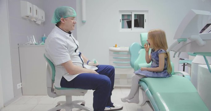 Little girl showing her aching tooth to pediatric dentist