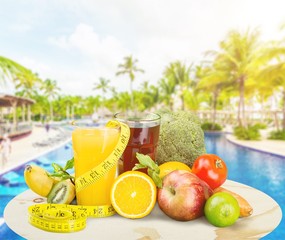 Glasses of fresh juice and fruits with vegetables and measuring tape