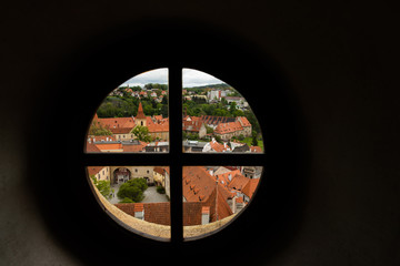 Fototapeta na wymiar View through the window on the tower of the castle and the view of Cesky Krumlov with the famous Cesky Krumlov Castle, the Church of the World Heritage Site