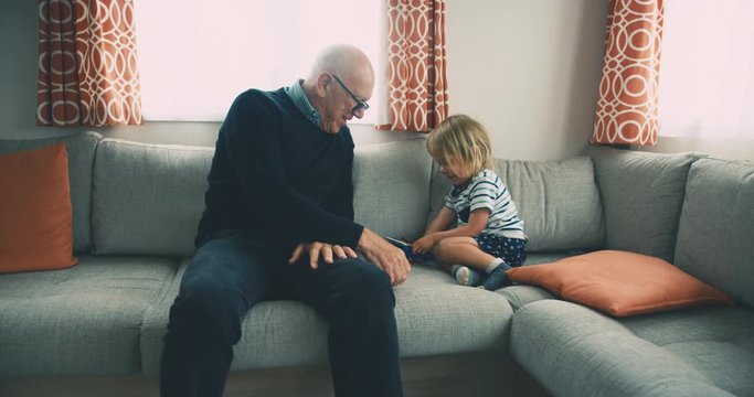 Toddler and grandfather playing with toy helicopter by the window