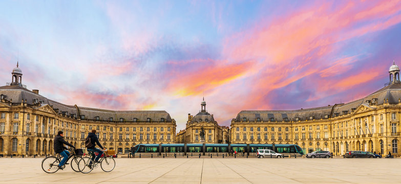 Deux cyclistes et le tramway qui passent devant la place de la bourse &agrave; Bordeaux en Gironde, Nouvelle-Aquitaine, France	