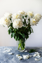 Bunch of amazing peonies in the vase on white wall background