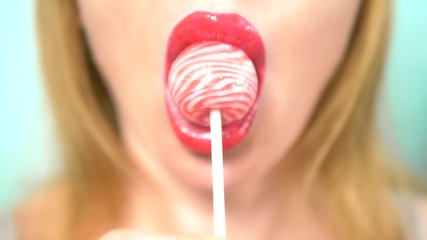 close-up, female sexy lips with red lipstick suck big pink round lollipop. copy space. blue background