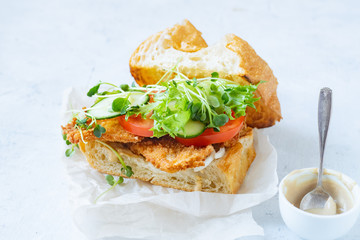 Sanwich with fried chicken on chiabatta with tomatoes, cheddar cheese, cucumber, onion, salad and microgreens