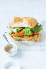 Sanwich with fried chicken on chiabatta with tomatoes, cheddar cheese, cucumber, onion, salad and microgreens