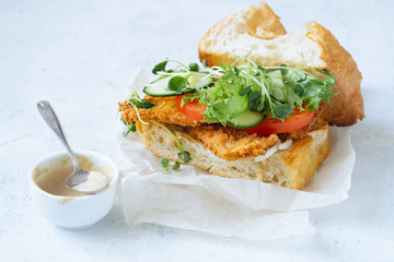 Sanwich with fried chicken on chiabatta with tomatoes, cheddar cheese, cucumber, onion, salad and microgreens