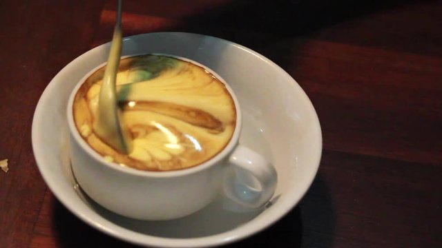 a hand stirring traditional vietnamese egg coffee made of raw egg yolk and condensed milk